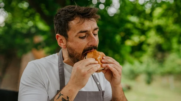 Mand nyder smagen af en hjemmelavet BBQ burger