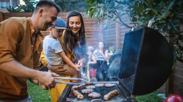 Ung glad familie holder en grillfest i baghaven