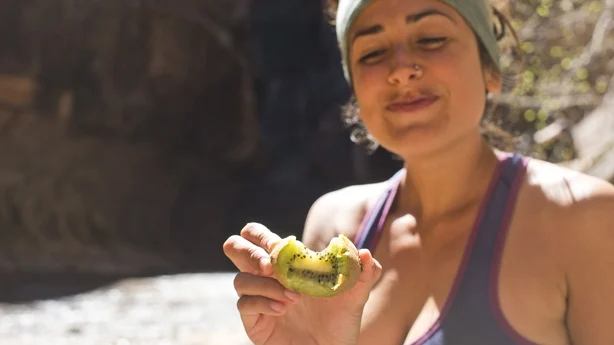 sund kvinde vandrer og spiser kiwi
