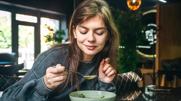 kvinde spiser grøntsagssuppe på en cafe